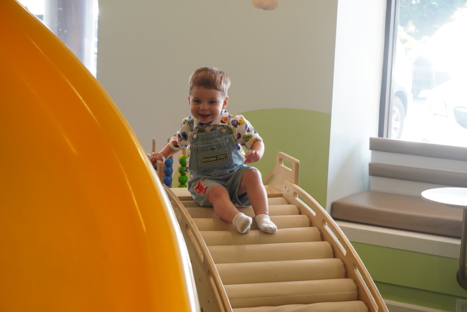 A toddler on a slide in a playroom